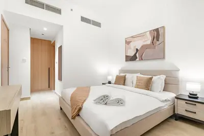 a bedroom with a large white bed with two towels on it at Bright 2BR Retreat Balcony & Pool Near Jumeirah Village Circle in Dubai