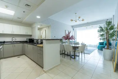 a kitchen and living room with a table and chairs at Nasma Luxury Stays - Sky-High Serenity in Stylish 2BR Retreat in Dubai