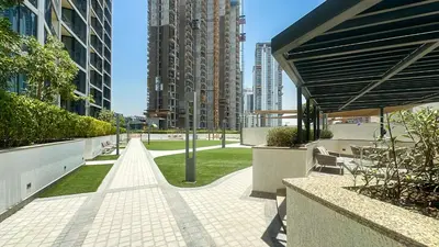 a walkway in the middle of a city with buildings at Spacious 2BR, Sobha Waves, Family-Friendly Stay - 3AB11 in Dubai