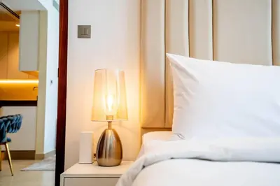 a bedroom with a bed with a lamp on a night stand at Amazing Pool LUX Location 1 Bedroom Apartment in Dubai