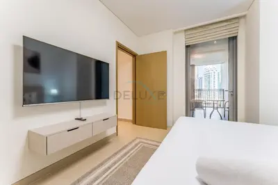 a white bedroom with a large flat screen tv on a wall at Short walk to Marina Walk and JBR Beach, close to Bluewaters Island and Ain Dubai, 5242 Tower 1, Dubai Marina by Deluxe Holiday Homes in Dubai