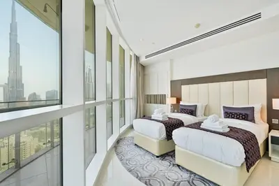 two beds in a room with a large window at Stylish 2BR - Near Burj Khalifa & City Views in Dubai