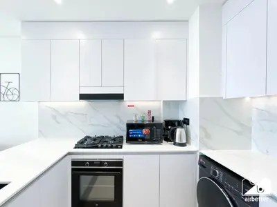a white kitchen with a stove and a microwave at Bright and Modern 1BR Binghatti Amber with City View in Dubai