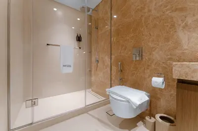 a bathroom with a shower and a white toilet at Seafront 3BR with maid's - Grand Bleu by Elie Saab in Dubai