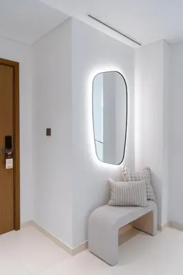 a white room with a chair and a mirror at Seafront 3BR with maid's - Grand Bleu by Elie Saab in Dubai