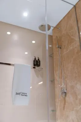 a bathroom with a shower with a glass door at Seafront 3BR with maid's - Grand Bleu by Elie Saab in Dubai