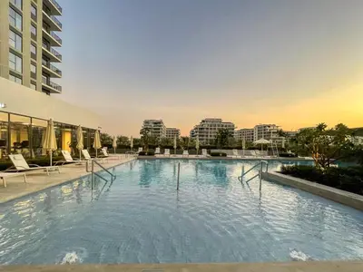 a large swimming pool with chairs and buildings at GuestReady - Golden paradise in Dubai Hills in Dubai