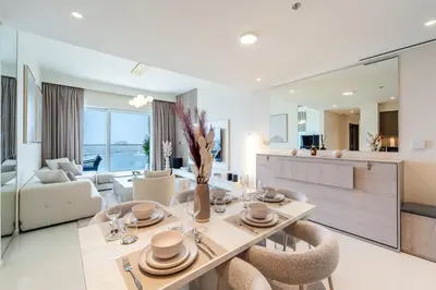 a dining room and living room with a table and chairs at Elie Saab Tower Luxury Apartment in Dubai