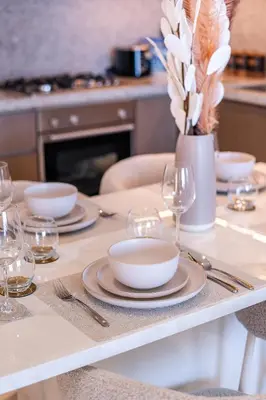 a table with plates and glasses and a vase with flowers at Elie Saab Tower Luxury Apartment in Dubai