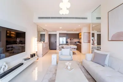 a living room with a couch and a dining room at Elie Saab Tower Luxury Apartment in Dubai