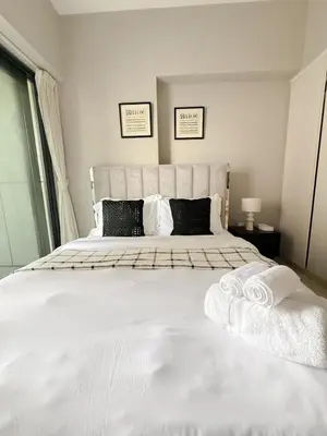 a bedroom with a large white bed with towels on it at Sunset Balcony - Sleeps 4 - Water View - Pool n Gym - 1BR in Dubai