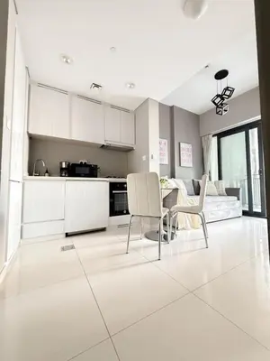 a kitchen with white cabinets and a table and chairs at Sunset Balcony - Sleeps 4 - Water View - Pool n Gym - 1BR in Dubai