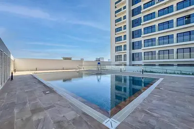 a large building with a swimming pool in front of a building at Contemporary Studio Getaway in Jebel Ali in Dubai
