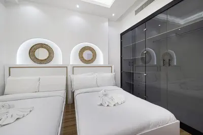 two beds in a white room with mirrors at Chic 2BR Steps to JBR Beach in Dubai