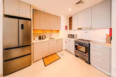 a kitchen with white cabinets and a stainless steel refrigerator at Creek Crescent by Emaar, Dubai Creek Harbour in Dubai