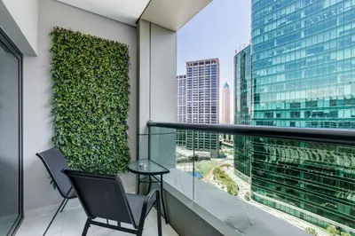 a balcony with two chairs and a green wall at Knokey Cozy Studio Apartments in Business Bay in Dubai