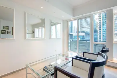 a glass table and chairs in a room with windows at Modern 1BR with Balcony and Marina Views in Al Majara 2 in Dubai