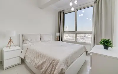 a white bedroom with a bed and a large window at Manchester Tower Dubai Marina in Dubai