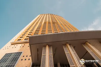 a tall gold building with a blue sky in the background at Emmar fashion avenue Dubai mall in Dubai