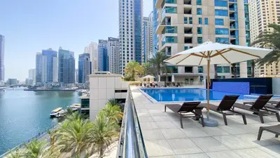 a swimming pool with chairs and an umbrella on a building at Sky High luxury Stay in Dubai Marina ,with Marina View, High Floor, Modern Design, Pool Access by Stay Vista! Up to 6 Guests in Dubai