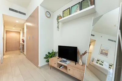 a living room with a flat screen tv on a wooden cabinet at PVH - Cozy Studio in Azizi Riviera 43 in Dubai