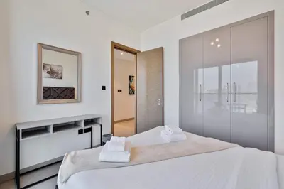 a white bedroom with a large bed and a mirror at PVH - Sobha Waves - Serene 1BR minutes to Downtown in Dubai