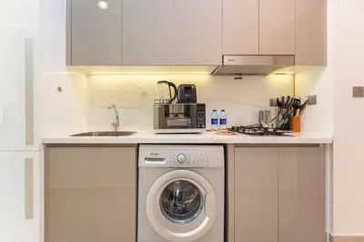 a kitchen with a washing machine and a sink at PVH - Modern Studio Near Downtown - Azizi Riviera in Dubai