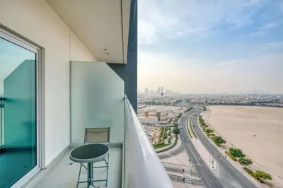 a balcony with a table and a view of a city at PVH - Homely Studio near Miracle Garden in Dubai