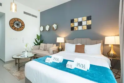 a bedroom with a large bed and a couch at PVH - Homely Studio near Miracle Garden in Dubai