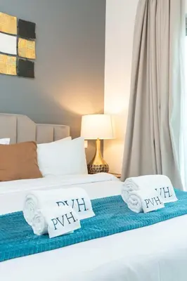 a bedroom with two beds with towels and a lamp at PVH - Homely Studio near Miracle Garden in Dubai