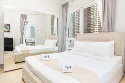 a white bedroom with two beds and a large window at PVH - Sunny Studio near Metro - Madison Residency in Dubai