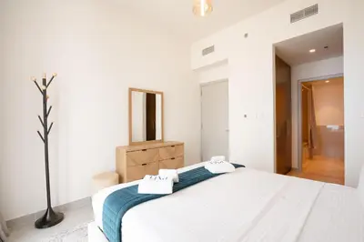 a white bedroom with a bed and a mirror at PVH - Forte Tower 1 - Opulent 2BR near Dubai Mall in Dubai