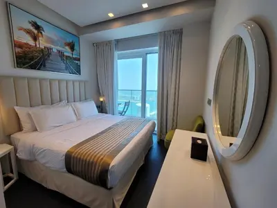 a hotel room with a bed and a large window at Damac Heights - Blue Ocean Holiday Homes in Dubai