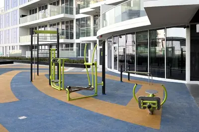 a gym in front of a tall building at Luxury 3Br Apts with Private Pool in Gemz by Simply Comfort in Dubai