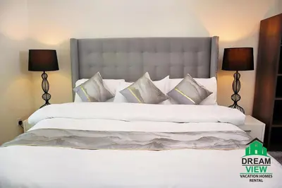 a bedroom with a large white bed with two lamps at Souk Al Bahar connected to Dubai Mall, Burj khalifa Partial View Dream View Holiday Home Rental in Dubai