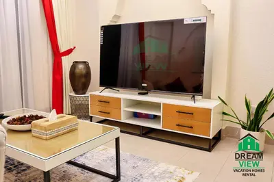 a living room with a large television on a dresser at Souk Al Bahar connected to Dubai Mall, Burj khalifa Partial View Dream View Holiday Home Rental in Dubai