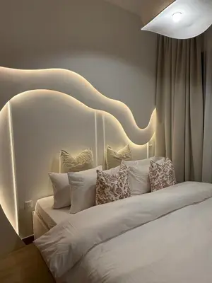 a bedroom with a white bed with a curved headboard at Appartement moderne et élégant in Dubai