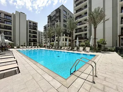 a swimming pool with chairs and trees and buildings at Chic Dubai Apartment Creek View Peaceful Vibes in Dubai