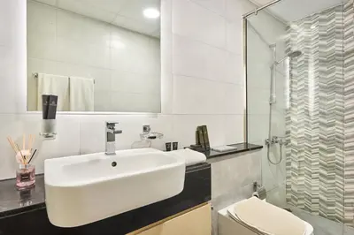 a white bathroom with a sink and a shower at One Bedroom Apartment in Binghatti Avenue by The S Holiday Homes in Dubai