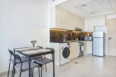 a kitchen with a table and a sink and a dishwasher at One Bedroom Apartment in Binghatti Avenue by The S Holiday Homes in Dubai