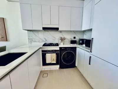 a white kitchen with a stove and a dishwasher at Cozy 1br In Jvc Pool, Balcony & Free Parking in Dubai
