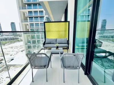 two chairs and a table on a balcony with windows at Cozy 1br In Jvc Pool, Balcony & Free Parking in Dubai