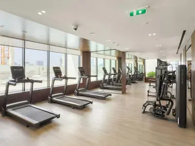 a gym with a row of treadms and elliptical machines at Silkhaus New 1BDR Retreat at Binghatti Tulip in JVC in Dubai