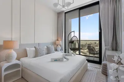 a white bedroom with a bed and a large window at Elegant 1 Bedroom in Binghatti Tulip - JVC in Dubai