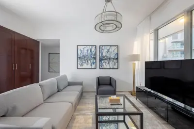 a living room with a couch and a tv at Burj and Fountain view 3BR plus maids room in Dubai