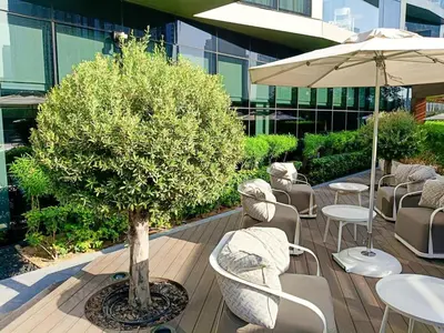 a tree sitting on a deck with chairs and an umbrella at ADDRESS Residences Opera 2BR Tower 1 - EPIC 30th floor Burj Khalifa view byBLCK with DXB AIRPORT VIP Shuttle option in Dubai