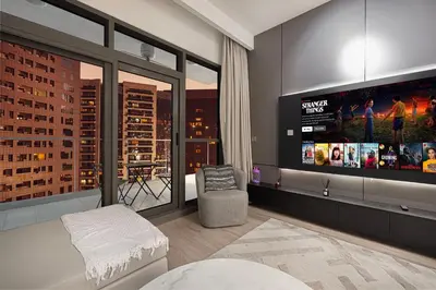 a living room with a tv and a large window at Modern 1BR in Avanti with Pool & Gym in Dubai