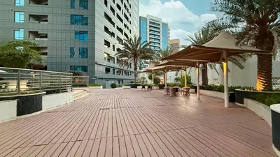 a walkway with tables and umbrellas in a city at Modern 1BR in Avanti with Pool & Gym in Dubai