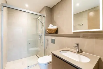 a bathroom with a toilet and a sink and a shower at Sobha Waves Grande Big 1BR apt Burj Khalifa views! in Dubai