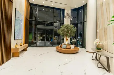 a lobby with a tree in a large building at Sobha Waves Grande Big 1BR apt Burj Khalifa views! in Dubai